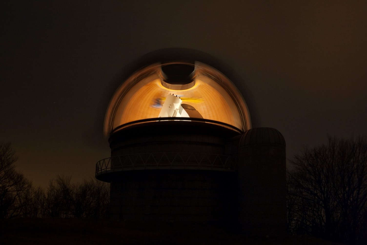 Transzparens csillagászat. A hosszú expozíciós felvételen a kupola körbe forgatásával láthatóvá válik minden, ami előtt a nyitott kupolarés elhaladt, így a belül megvilágított teljes kupola és a Schmidt távcső.